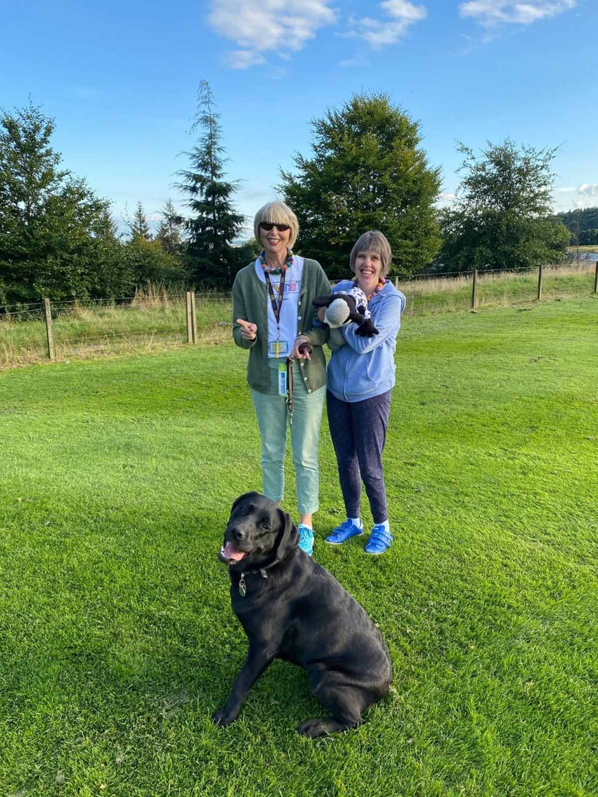 2 ladies in the field with their dog