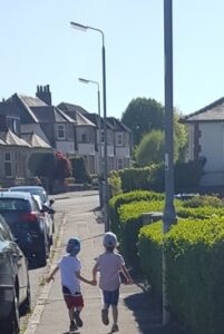 2 children walking hand in hand on the pavement