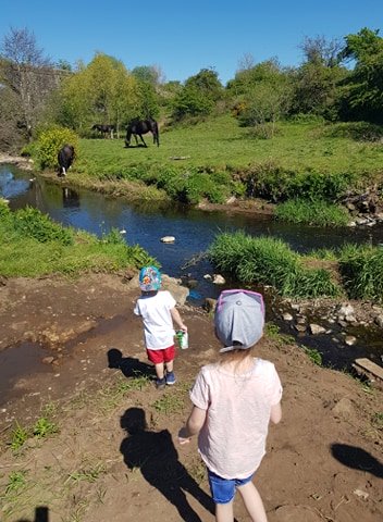 2 children enjoying a walk by a stream
