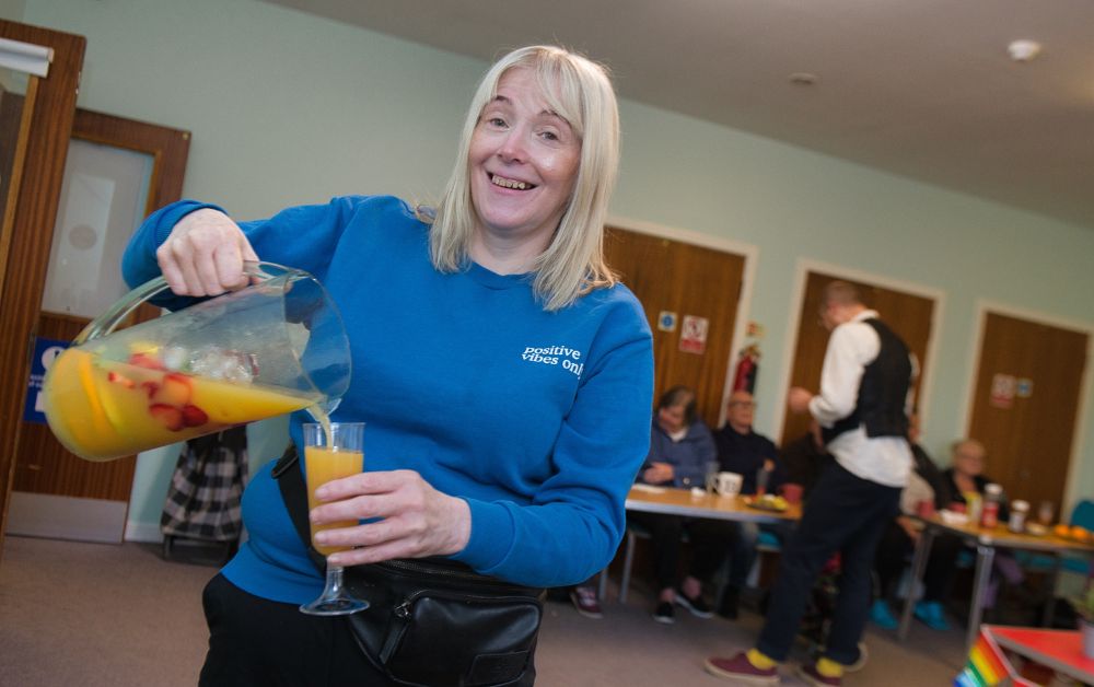 person pouring a glass of juice with a big smile