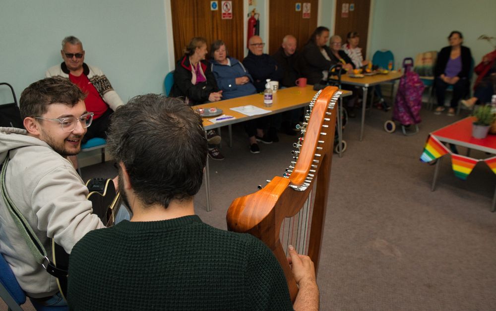 two musicians playing to a group of community members
