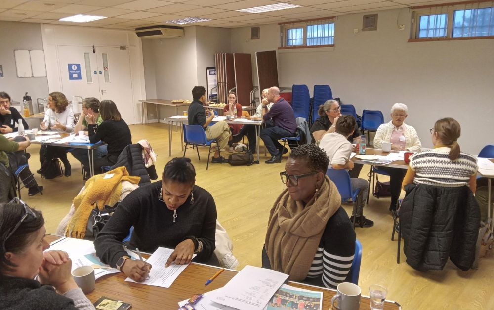 group of people in a room chatting and writing on paper
