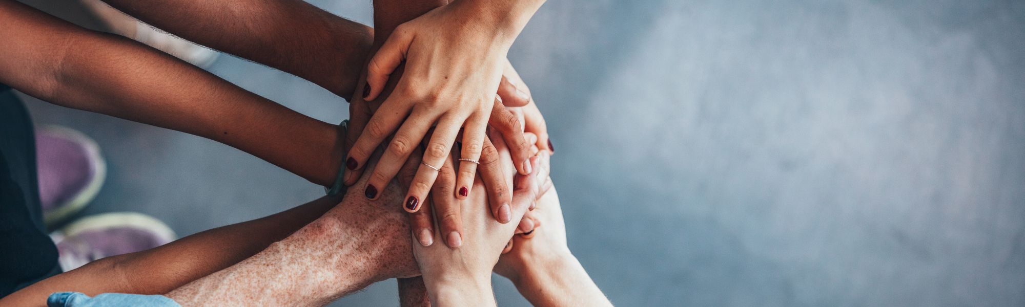 different people's hands in together and overlapping in unity
